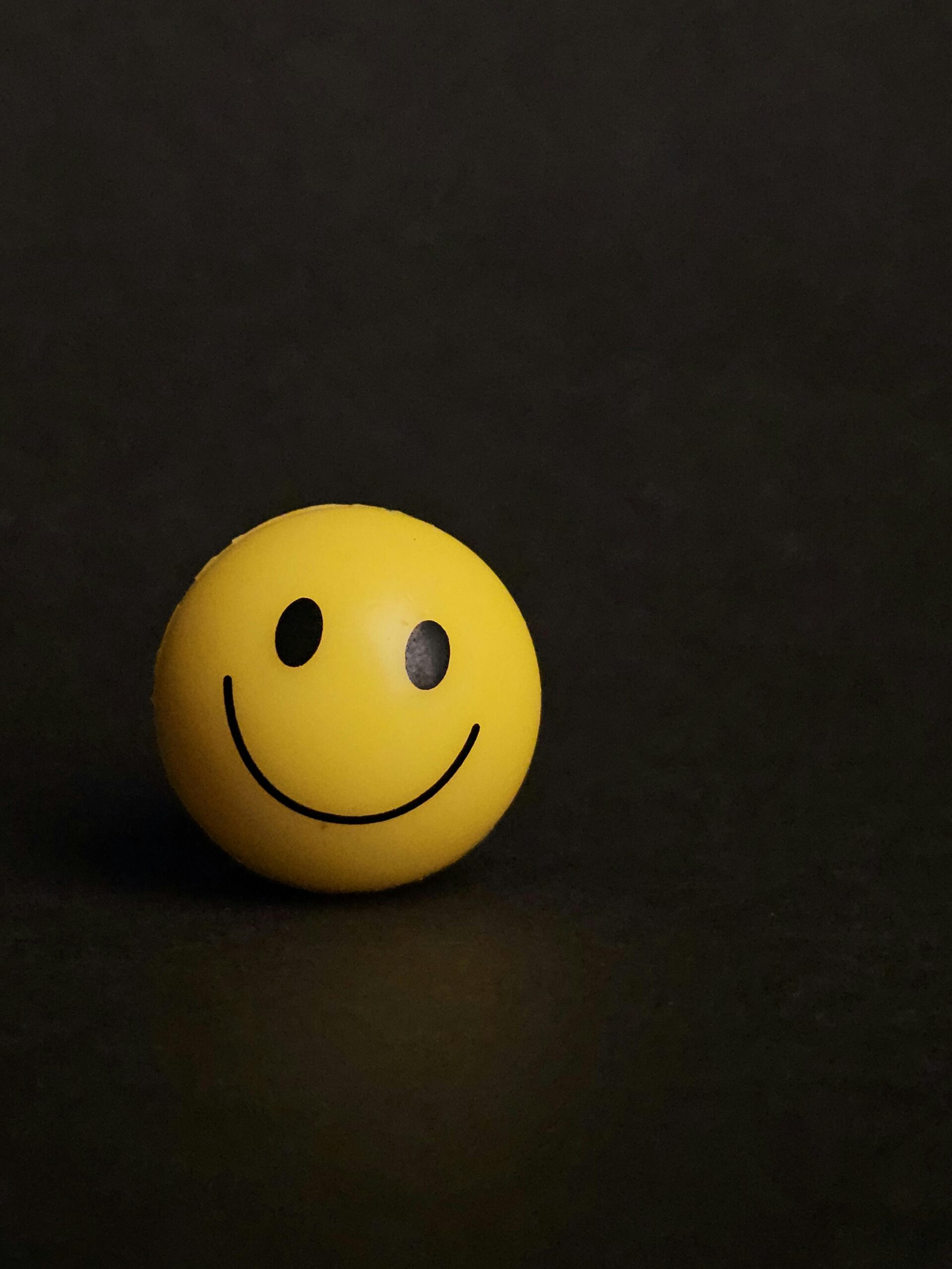 Yellow smiley face ball on dark background, evoking happiness and simplicity.