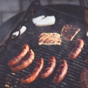 Delicious sausages and steak grilling over an outdoor barbecue with a smoky, chargrilled finish, perfect for a summer cookout.