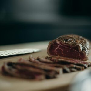 A close-up view of sliced red meat on a wooden cutting board, ideal for culinary and food-related needs.