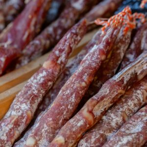 A detailed close-up of traditional Italian salami sticks arranged in rows, showcasing their texture.